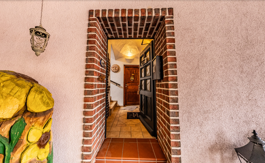 Eingang der Pension Kluge in Freiberg mit gemauertem Torbogen und offen stehender Tür.