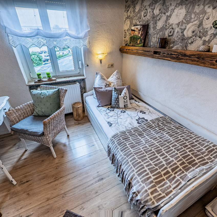 Einzelzimmer der Pension Kluge in Freiberg mit hellem Fenster, Schreibtisch und liebevoller Einrichtung.