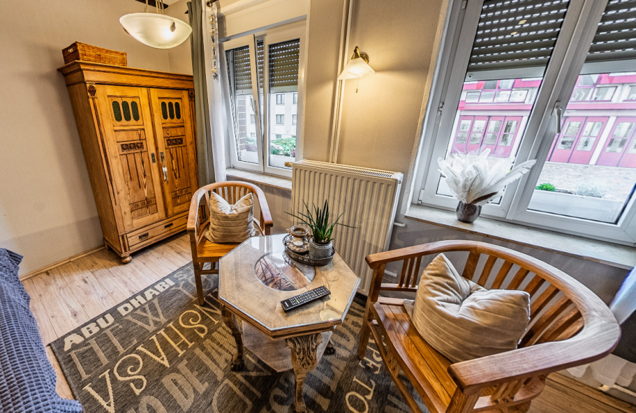 Zimmer der Pension Kluge in Freiberg mit Holzofen, Fernseher und gemütlicher Sitzecke.