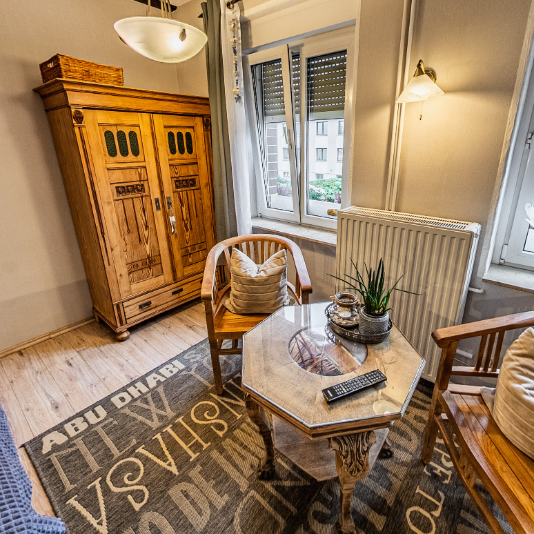 Zimmer der Pension Kluge in Freiberg mit Holzmöbeln, Sesseln und warmem Licht für entspannte Abende.